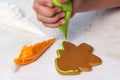 Baking holiday cookies. The child decorates homemade gingerbread in the form of a Christmas tree with green glaze. Royalty Free Stock Photo