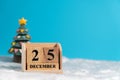 Christmas tree backside wooden block calendar set on the Christmas date 25 december on white wool and blue background. Copy space