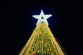 Christmas tree with big white star topper decorated yellow garlands and colorful decorative bulbs