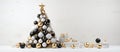 A Christmas tree with black, white, and gold decorations sits on a table Royalty Free Stock Photo