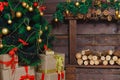Christmas tree, boxes of gifts. Wooden brown wall with decorative logs coniferous branches