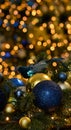 Christmas tree branch with beautiful shiny blue, gold balls and blue bird on a golden festive bokeh background. Christmas backgrou Royalty Free Stock Photo