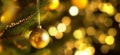 Christmas tree branch with hanging gold christmas ball on Xmas bokeh lights backdrop. Focus on ball. Royalty Free Stock Photo