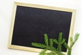 Christmas tree branch lie in the corner of black chalkboard with wooden frame. Royalty Free Stock Photo