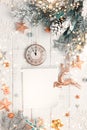 Christmas tree branch with pine cone in snow, retro style clock and notepad on a white wooden background. Winter or Christmas Royalty Free Stock Photo