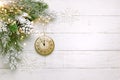 Christmas tree branch with pine cone in snow and retro style clock on a white wooden background. Winter or Christmas festive Royalty Free Stock Photo