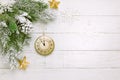 Christmas tree branch with pine cone in snow and retro style clock on a white wooden background. Winter or Christmas festive Royalty Free Stock Photo