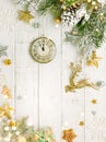 Christmas tree branch with pine cone in snow and retro style clock on a white wooden background. Winter or Christmas festive Royalty Free Stock Photo