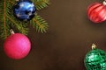 Christmas tree branch with pink, blue, red wavy and green ribbed ball on a dark background Royalty Free Stock Photo