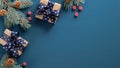 Christmas tree branch with red berries and gift box over blue xmas background. Flat lay, top view, copy space. Christmas banner Royalty Free Stock Photo