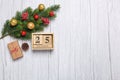 Christmas tree branch with toys and gifts and wooden calendar december 25 on wooden background Royalty Free Stock Photo