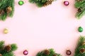 Christmas tree branches, cones and balls on pastel pink background