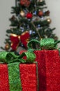 Red gift boxes with green lace and christmas tree in the background