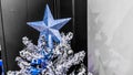 Christmas tree color silver white with blue star and decorations against black and white wall. Christmas ornaments Royalty Free Stock Photo