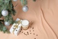 A Christmas tree, decorated with balls, a gift box, a glass with coffee and milk on the background of flesh-colored Royalty Free Stock Photo