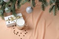 Christmas tree decorated balls, a gift box, a glass mug with coffee and milk on the background of flesh-colored waves Royalty Free Stock Photo