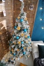 Christmas tree decorated with blue balls and dried oranges. wood in the interior with screen, light floor and blue wall Royalty Free Stock Photo