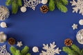 Flat lay composition of silver christmas baubles, snowflakes, spruce branches and fir cones on deep blue background Royalty Free Stock Photo