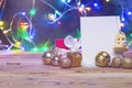 Christmas tree decorations and gift box with a blank card on a wooden table. Xmas toys with blank paper over Christmas tree and