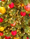 Christmas tree detail, baubles, lights and golden star hanging close up Royalty Free Stock Photo