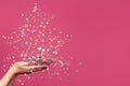 Christmas tree from falling confetti on woman hands against bright pink banner background