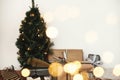 Christmas tree with festive stylish gifts in golden lights bokeh in white room. Happy Holidays. Merry Christmas.Winter holidays Royalty Free Stock Photo
