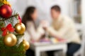 Christmas tree on foreground with defocused romantic young couple sit at the table, happy people and love concept, new year holida