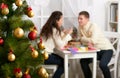 Christmas tree on foreground with defocused romantic young couple sit at the table, happy people and love concept, new year holida