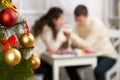 Christmas tree on foreground with defocused romantic young couple sit at the table, happy people and love concept, new year holida