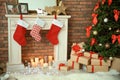 Christmas tree and gifts near decorative fireplace with stockings indoors