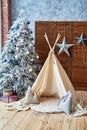 Christmas tree with gifts and wigwam in child room, copy space. Christmas decorations. Childen room interior with decorated play.