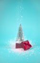 Christmas tree growing out of gift box, covered with falling snow. On snowy blue background Royalty Free Stock Photo