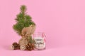 Christmas tree in jute bag with fir cone, candle saying `Merry Christmas` and snowflake ornament