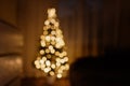 Christmas tree in lights in blur stands near the bed Royalty Free Stock Photo