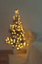 Christmas tree in lights in blur stands near the bed Royalty Free Stock Photo