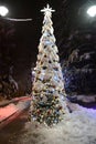 Christmas tree in lights and snow in park alley with street lamps at night Royalty Free Stock Photo