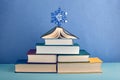 A Christmas tree made of elegant thick books in multi-colored covers, decorated with a large blue snowflake. Royalty Free Stock Photo