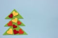 Christmas tree made of felt fabric and decorated with hearts on blue background. Royalty Free Stock Photo