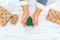 Christmas tree made of felt in hands  with gift on a white wooden background. Flat lay Royalty Free Stock Photo