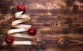 A Christmas tree made of gold ribbon decorated with red round toys on a dark wooden background. Flat lay. Royalty Free Stock Photo