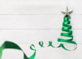 Christmas tree made of green satin ribbon scroll with silver star isolated on white pine wood background with clipping path Royalty Free Stock Photo