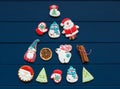 Christmas tree made with homemade gingerbread cookies on plate on classic blue wooden background. Snowflake, star, tree, snowman