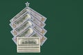 Christmas tree made from hundred dollar bills with white plastic star on top on green background. Copy space. Top view. New Year Royalty Free Stock Photo