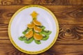 Christmas tree made of kiwi slices and mandarin lobules on wooden table. Top view. Royalty Free Stock Photo