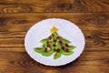 Christmas tree made of kiwi slices and pomegranate on wooden table. Creative idea for Christmas and New Year festive desserts. Royalty Free Stock Photo