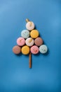 Christmas tree made of macaron cookies with crown on top. Christmas arrangement on blue background. Top view, flatlay, copy space