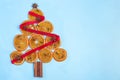 Christmas tree made from orange candied slices, cinnamon sticks, anise stars, and cloves, decorated with red ribbon, on blue Royalty Free Stock Photo