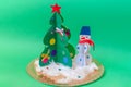 Christmas tree made of paper and a snowman handmade on a green background. Children`s Christmas crafts. Beautiful Christmas gifts
