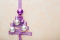 Christmas Tree made from purple ribbon, silver and purple baubles on pink pastel background , concept of Christmas time, winter,