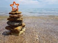 Christmas tree made of sea pebbles on the background of the sea. a red star adorns it. new year on the beach Royalty Free Stock Photo